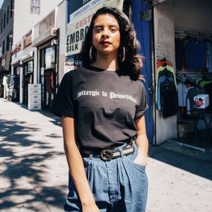 Viva La Bonita Women streetwear black t-shirt. Latina wearing black Allergic to pendejadas t-shirt in Los Angeles. Latina wearing gold hoop earrings.