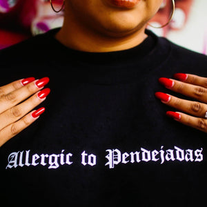 Viva La Bonita Women streetwear black sweatshirt. Allergic to pendejadas crewneck sweatshirt close up shot. Latina with red stiletto nails wearing black crewneck sweatshirt. 